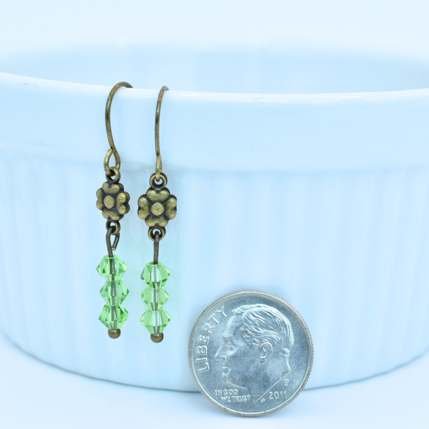 Pair of green beaded earrings with bronze floral tops, shown next to a dime for scale.
