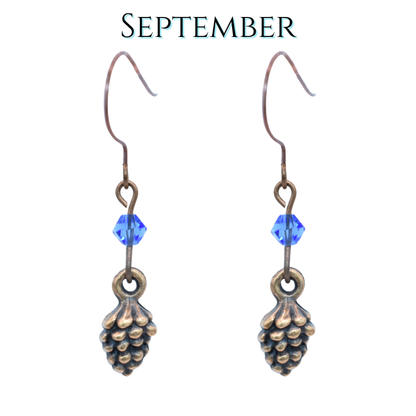 Pine cone-shaped earrings with sapphire blue crystal beads on a white background, labeled 'September'.