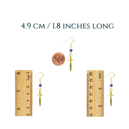 Gold earrings with a penny and ruler for scale on a white background