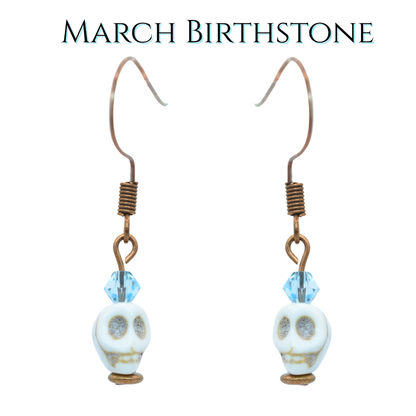 Skull-shaped earrings with light blue beads on a white background, labeled 'March Birthstone'.