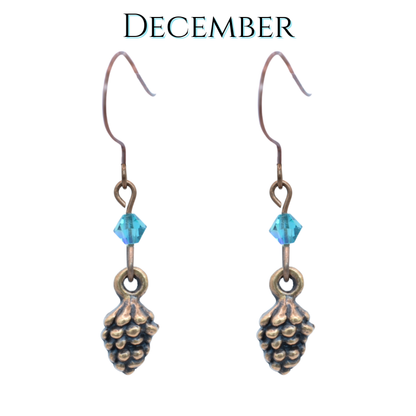 Pine cone-shaped earrings with teal blue crystal beads on a white background, labeled 'December'.