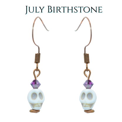 Skull-shaped earrings with purple beads on a white background, labeled 'July Birthstone'.