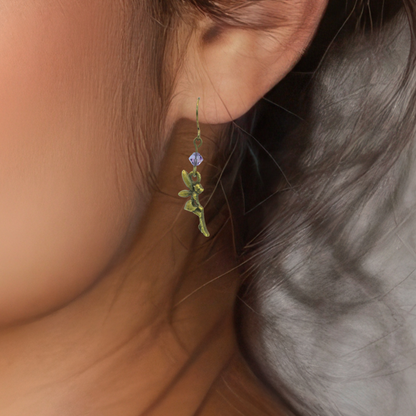 Close-up of a person wearing a fairy earring with a purple crystal bead.