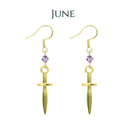 Gold dagger-shaped earrings with purple crystal beads on a white background, featuring the word 'JUNE'.
