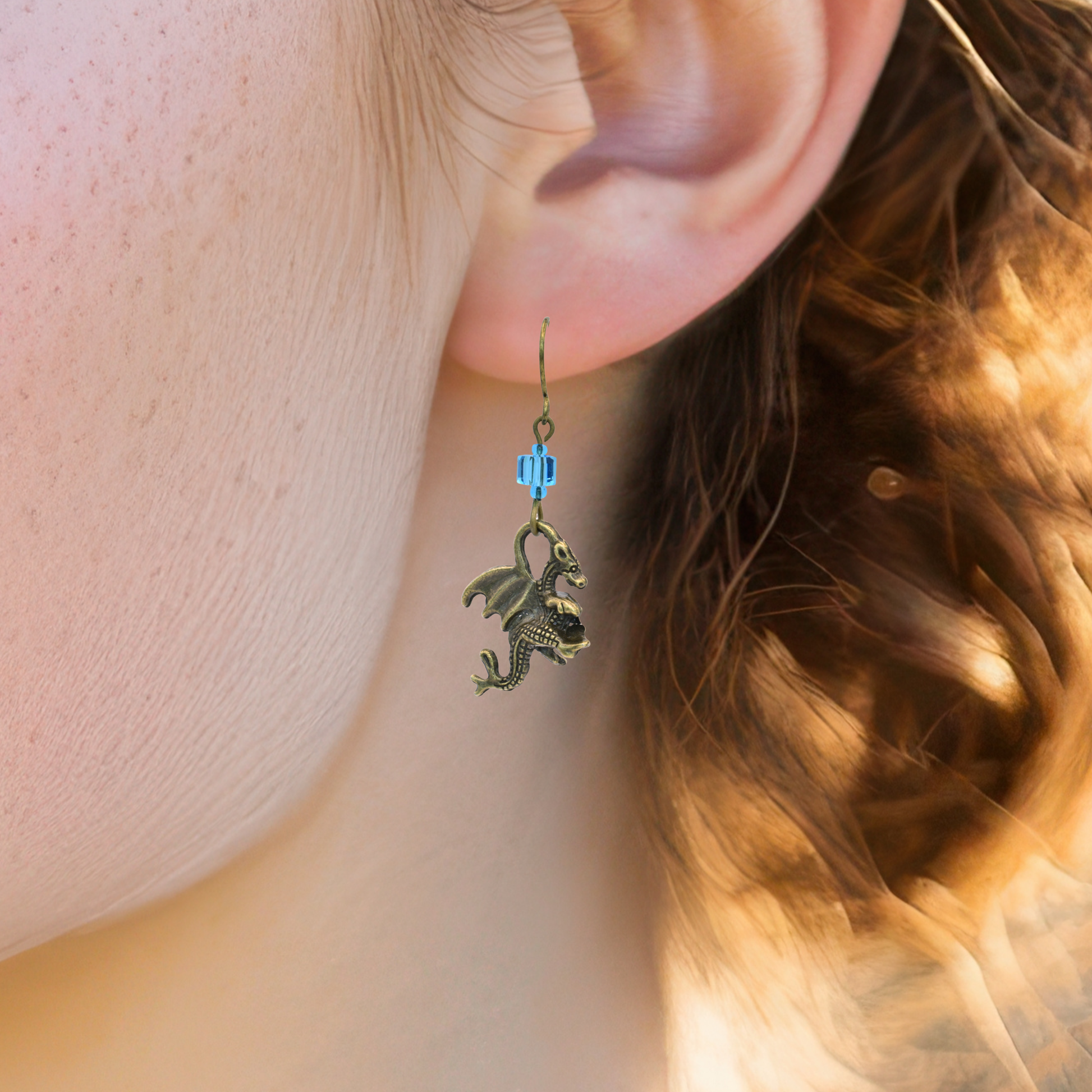 Close-up of an earring with a dragon design worn by a person.