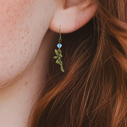 Close-up of a person wearing a fairy-shaped earring with a light blue crystal bead.