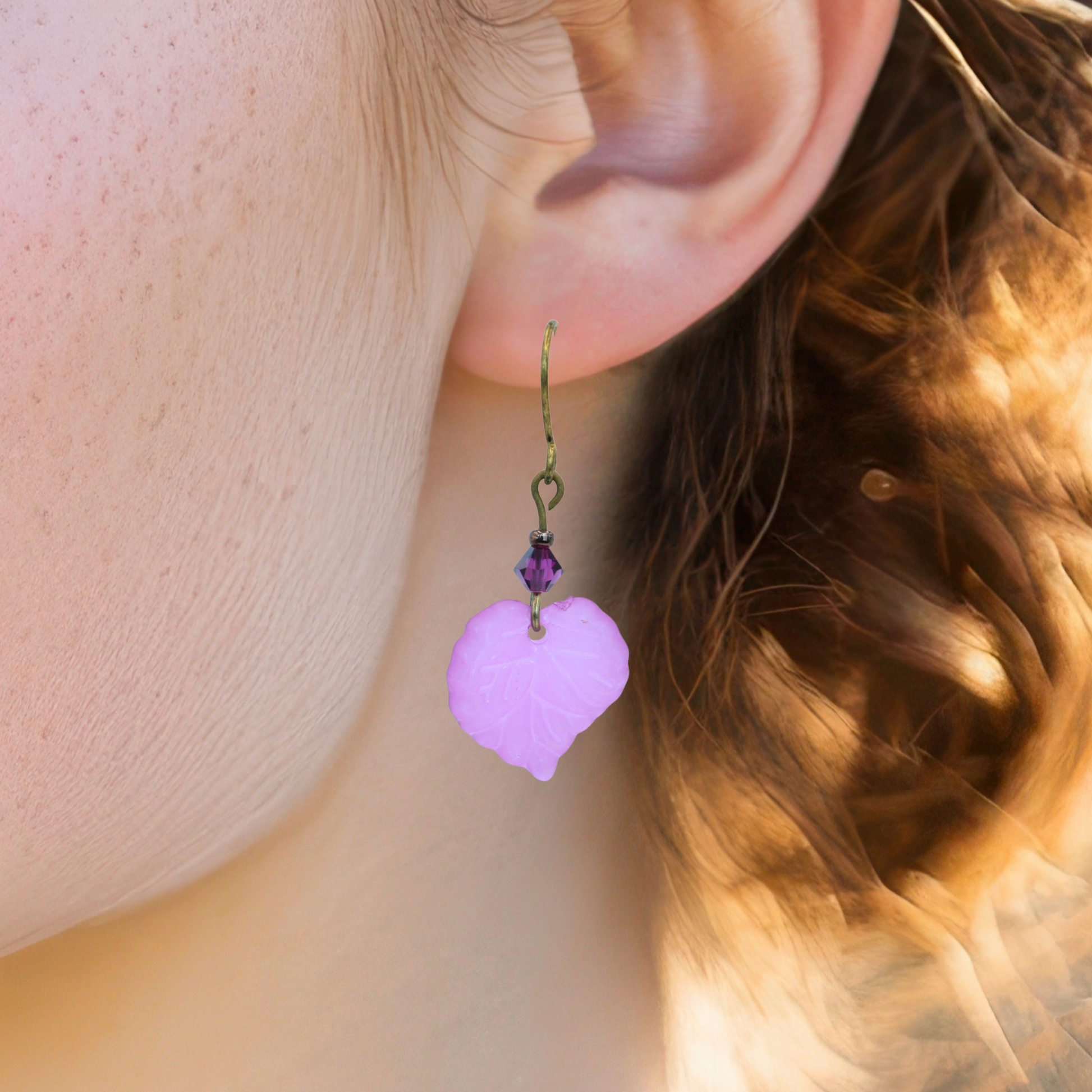 Close-up of a person wearing a pink leaf-shaped earring.