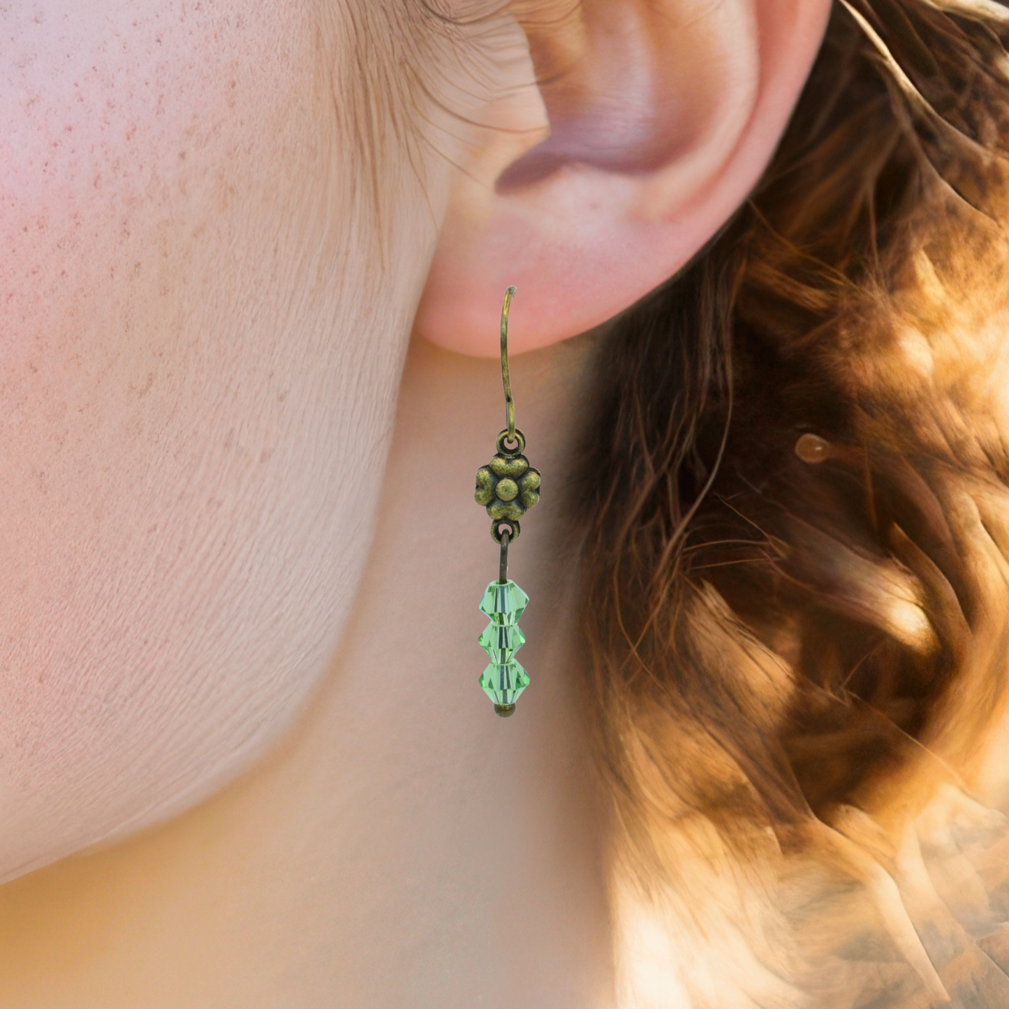 Close-up of a person wearing a green flower-shaped earring.