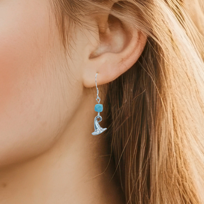 Close-up of an ear wearing a silver earring with a blue turquoise gemstone.