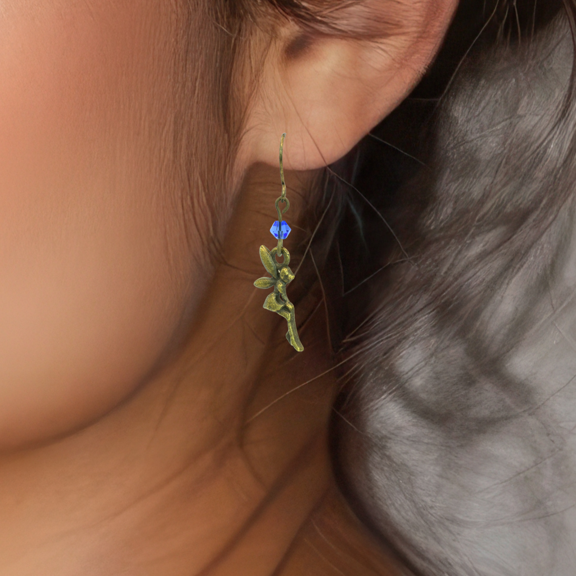Close-up of a person wearing a fairy earring with a blue crystal.