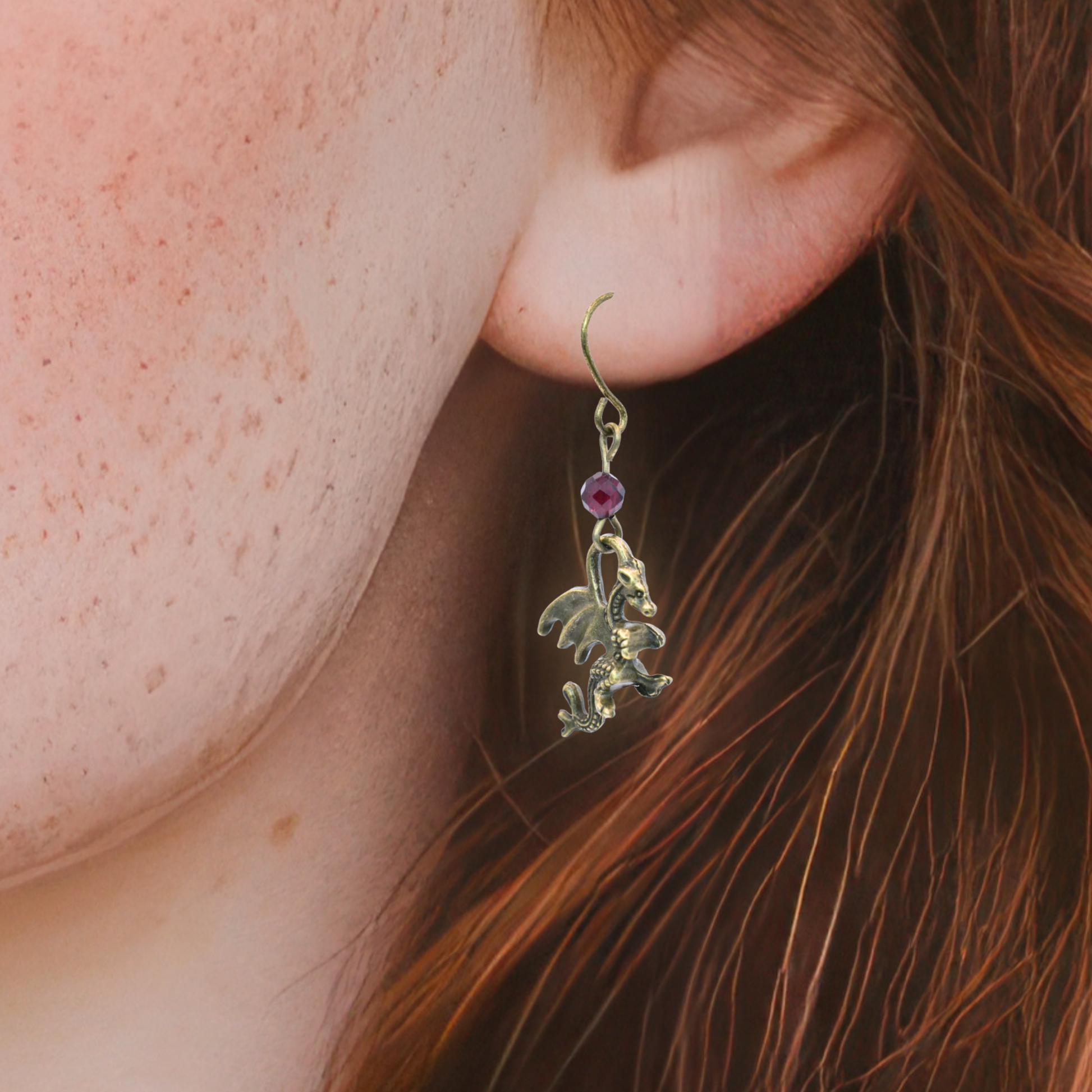 Close-up of an ear wearing a decorative earring with a red garnet gemstone.