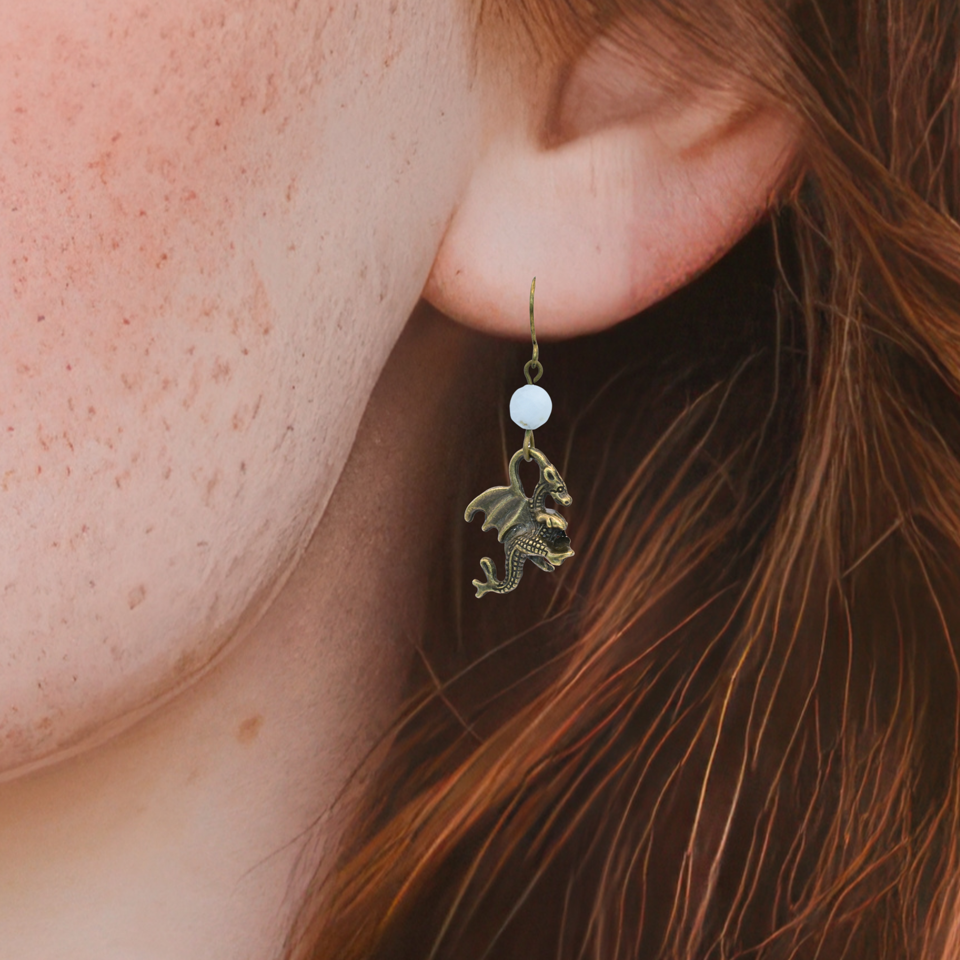 Close-up of an ear wearing a dragon-shaped earring with a blurred background