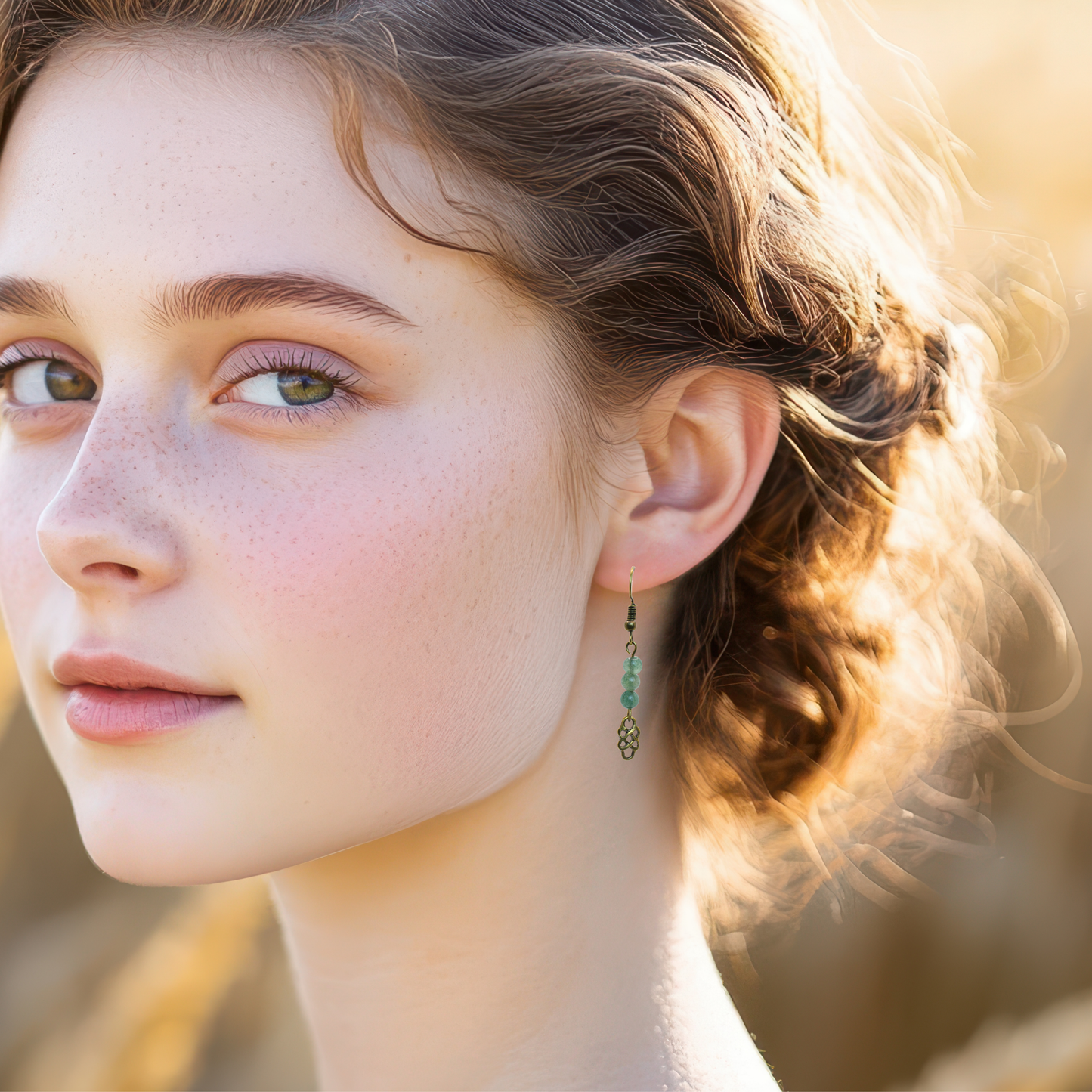 Close-up of a woman wearing earrings featuring antique gold Celtic knot charm and green jade beads with a blurred natural background