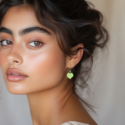 Close-up of a woman wearing August birthstone green leaf-shaped earring with a neutral background