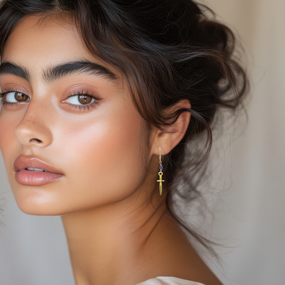 Close-up of a woman wearing a gold earring with a neutral background