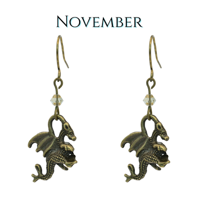 earrings featuring antique bronze dragon charms and tan crystal beads, image has text "November"