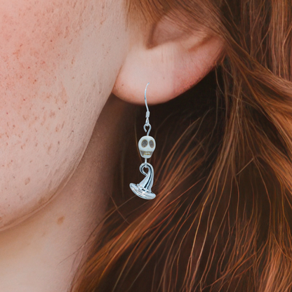 Close-up of a person wearing a silver skull earring with a wizard hat.