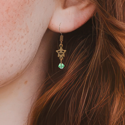 a person wearing a pair of earrings featuring antique copper smiley face stars with crystal beads