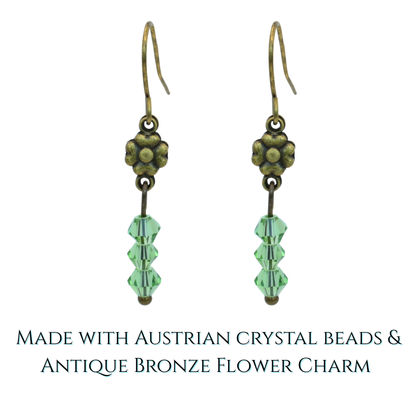Pair of earrings with green crystal beads and antique bronze flower charm on a white background.
