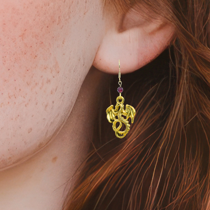 Gold dragon-shaped earring with a red gemstone worn by a person with red hair.