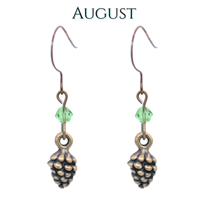 Pine cone-shaped earrings with light peridot green crystal beads on a white background, labeled 'August'.