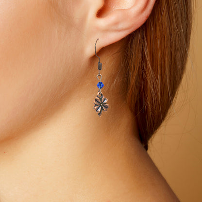 Close-up of an earring with a blue crystal bead on a beige background