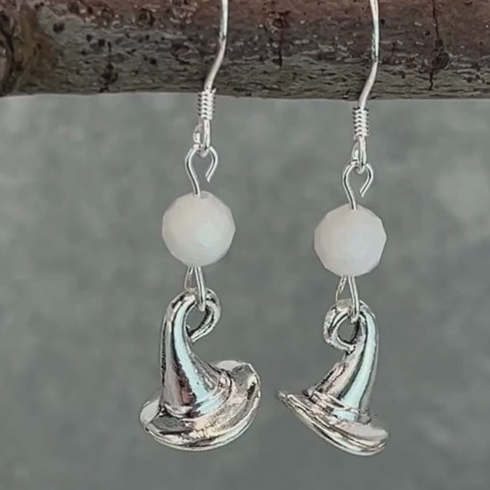 a video of silver earrings featuring white moonstone round faceted beads and witch hat charms