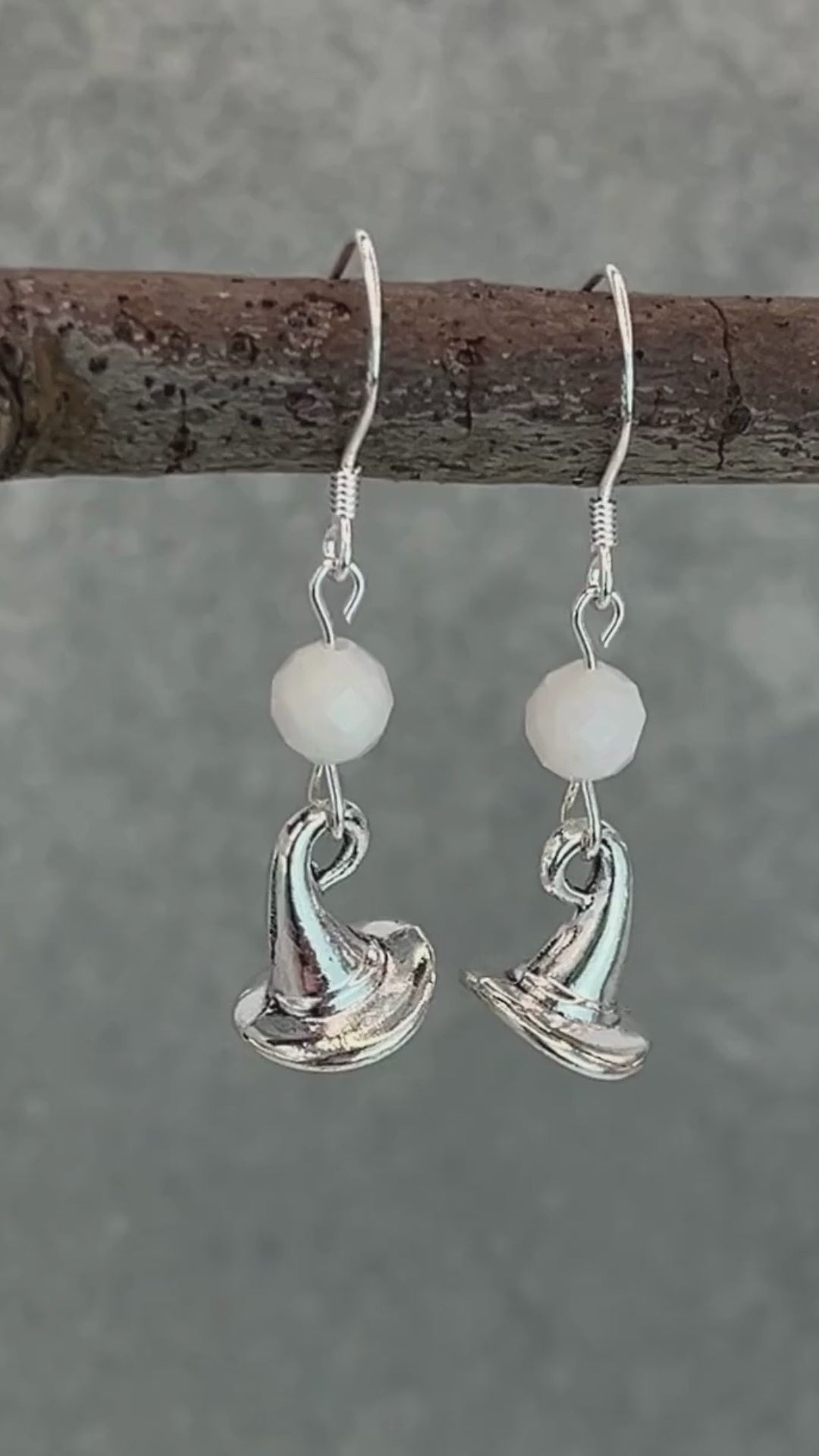 a video of silver earrings featuring white moonstone round faceted beads and witch hat charms